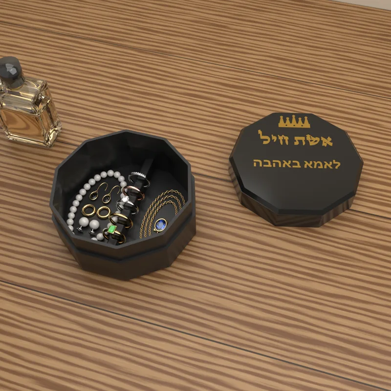 קופסת התכשיטים «אשת חיל» בצבע שחור, פתוחה ובה תכשיטים מסודרים, והמכסה עם ההקדשה לידה