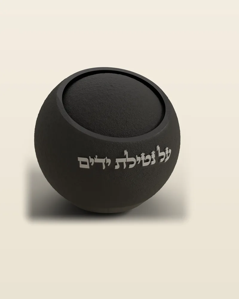 נטלה כדורית בצבע שחור עם הכיתוב «על נטילת ידים», באור צד שמראה את המרקם המחוספס