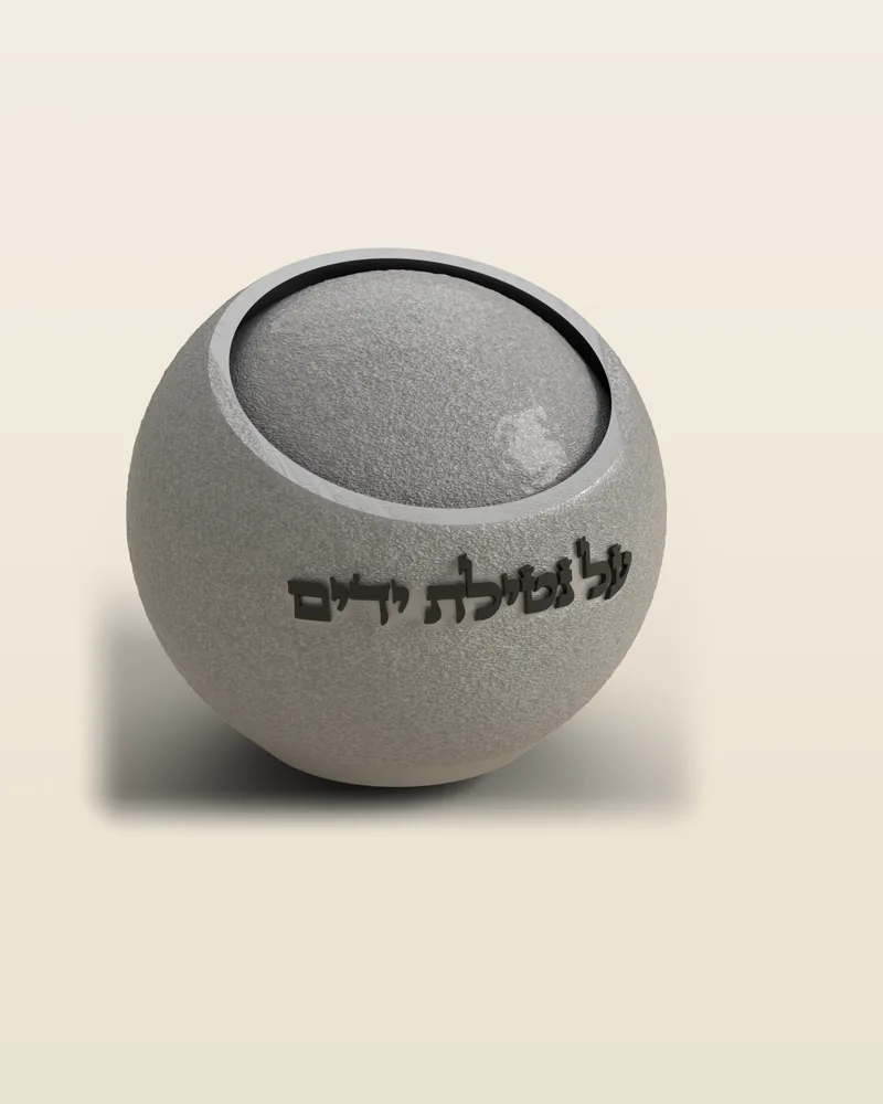 נטלה כדורית בצבע כסף עם הכיתוב «על נטילת ידים», באור צד שמראה את המרקם המחוספס